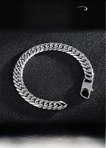 Détail du bracelet gourmette en acier inoxydable poli avec fermoir mousqueton sur cuir noir