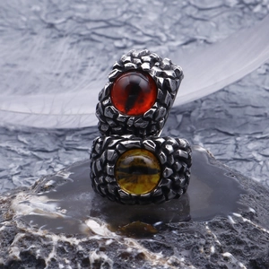 Macro shot of punk skull rings with red and yellow dragon eye stones on dark rock