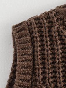 Detailed macro view showing chunky knit texture and ribbed hem of the brown sweater vest