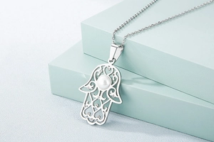 Détail du collier main de Hamsa argenté avec perle centrale sur supports d'expo