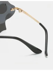 Close-up of curved golden metal temples and ergonomic black tips of rimless sunglasses