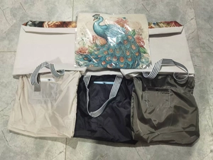 Flat lay of canvas tote bag with peacock floral embroidery and folding portable bags