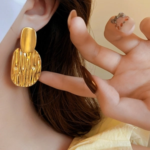 Gros plan de grandes boucles d'oreilles ovales dorées texturées portées par le modèle