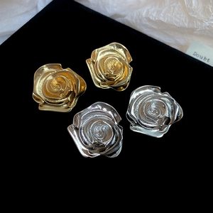 Dettaglio degli orecchini a forma di rosa in oro e argento su sfondo di velluto nero