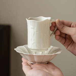 Bamboo relief ceramic teacup and saucer set with floral petal edge held in hand