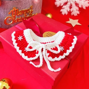 Detail of red and white crocheted pet Christmas collar with snowflake sequins and bow