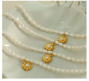 Detail view of freshwater pearl necklace with gold sunflower charms in a seashell plate