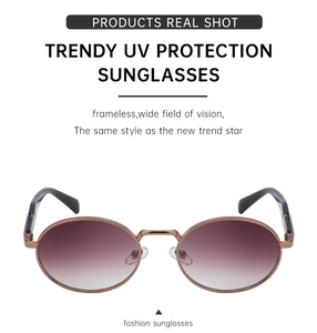 Detail view of oval sunglasses with brown gradient lenses and slim golden metal frames
