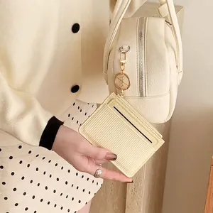 Cream striped card holder with gold hardware attached to a matching leather tote bag