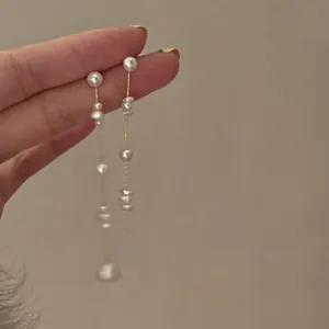 Detail of French chic freshwater pearl tassel earrings with delicate gold chain drop