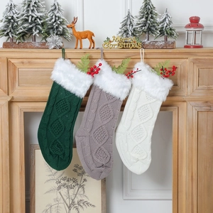 Trois chaussettes de Noël en tricot avec bordure en peluche accrochées à une cheminée
