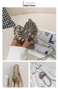 Detailed view of silver heart-shaped metal bag with shell texture and beaded handle