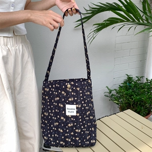 Detail of vintage floral canvas tote bag showing metal snap button and quilted fabric texture