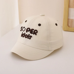 Detail of embroidered 'SÜPER idols' text on beige cotton baseball cap for kids