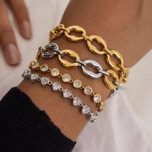 Close-up of four layered stainless steel bracelets in gold and silver with zircon