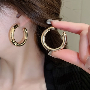 Close-up of golden C-shaped hoop earrings showing metallic luster and secure closure