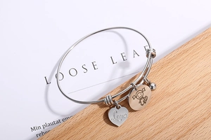 Detail of silver heart and girl charms on an adjustable stainless steel bracelet