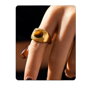 Macro shot of vintage texture gold ring featuring an oval tiger eye stone on finger