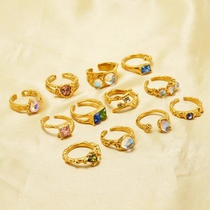 Array of gold adjustable moonstone rings with various gems on yellow fabric