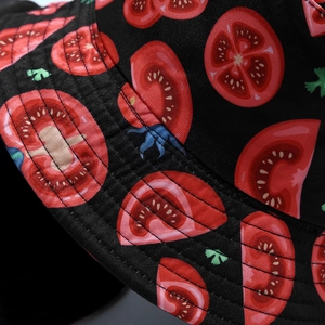 Detailed close-up of tomato patterns and stitching on a black reversible bucket hat
