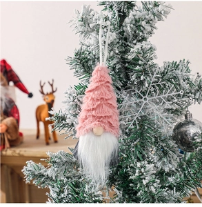 Detailed view of a pink plush Christmas gnome ornament hanging on a snowy festive tree