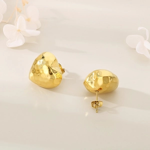 Detail of gold heart earrings showing unique hammered texture on white background