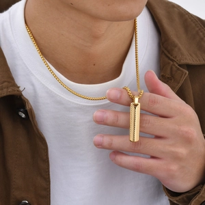 Macro shot of gold geometric bar pendant with textured finish and box chain on model