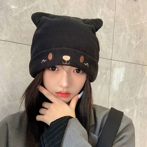 Detail of black knit beanie featuring cute animal ears and teddy bear facial embroidery