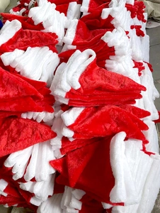 Massive pile of red plush Christmas hats with white trim in a warehouse setting