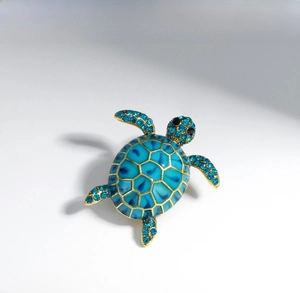 Macro detail of turtle brooch featuring blue enamel shell and sparkling crystal embellishments