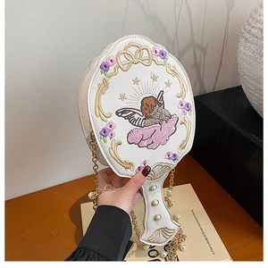 Detailed embroidery of an angel and pearl accents on a white designer handbag