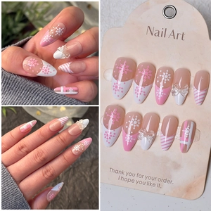 Macro detail of almond press on nails with 3D bows and snowflake patterns for winter style