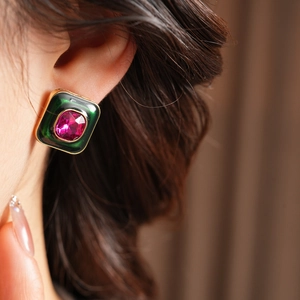 Close-up of vintage square gold earrings with green enamel and pink gemstone detail