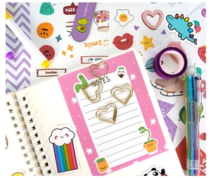 Flat lay of purple DIY journal set with glitter tape, heart clips, and cartoon stickers