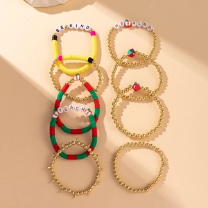 Detail of colorful beaded bracelets set with 'BE KIND' letters and apple charms