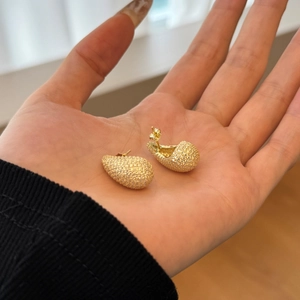 Detailed close-up of gold-plated teardrop earrings with pave-set shimmering crystals
