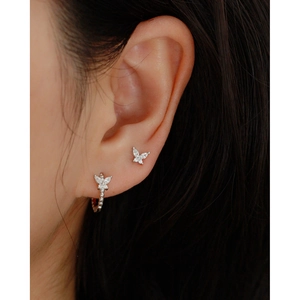 Close-up of sparkling silver butterfly stud earrings and ear cuffs on model's ear