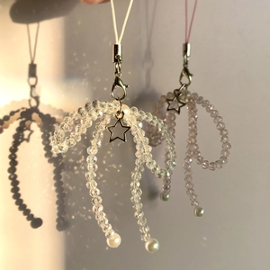 Close-up of handmade crystal bow phone charms with star pendants and soft shadows