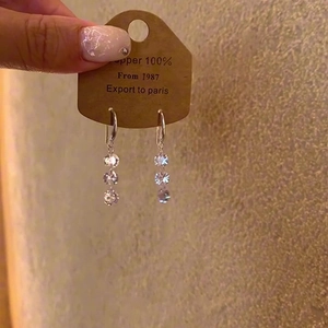 Macro shot of silver tassel earrings with sparkling zircon stones on a branded card
