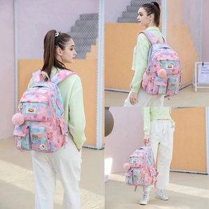 Detail view of tie-dye backpack with multiple zipper pockets and plush pendant accessory