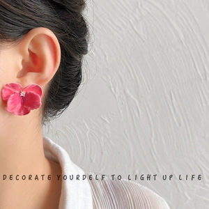 Elegant pink 3D petal earrings with 14K gold plating worn by a model in soft light