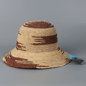 Dettaglio del cappello da sole in rafia intrecciata con trama a righe beige e marrone