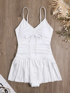Detailed view of white eyelet fabric swimsuit with ruffled bow and pleated skirt detail