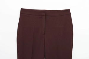Détail macro du pantalon bordeaux avec patte cachée et coutures de précision