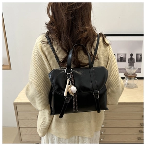Gros plan d'un sac à dos noir en similicuir avec pendentif baseball porté par un mannequin