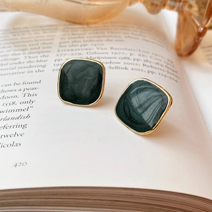 Close-up of vintage square stud earrings with dark green marble texture and gold edges