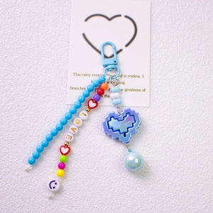 Macro detail of LOVE letter beads and blue pixel heart pendant on keychain strap