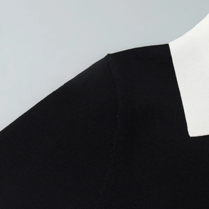 Gros plan du col polo blanc contrasté et de la maille noire fine sur l'épaule du haut