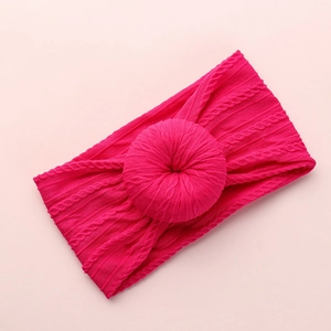 Detail of pink knitted baby headband featuring a soft cable stitch pattern and donut knot