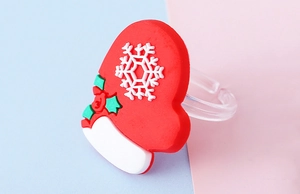 Detail eines roten PVC-Weihnachtshandschuh-Rings mit Schneeflocke und grünem Stechpalmenblatt